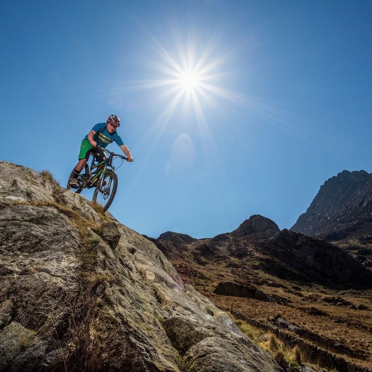 Mountain biker rolling down a rockface on the ridge