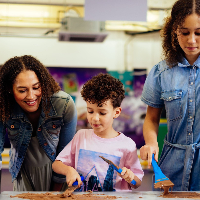 A boy, with curly hair, scraping chocolate off a table