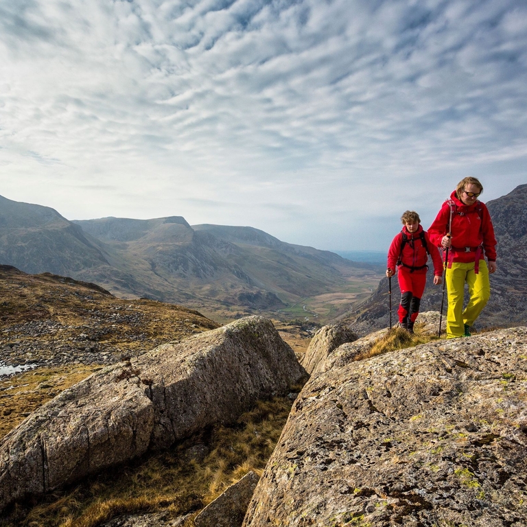 Two people walking to the high pass through the mountains