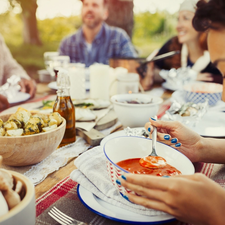 Friends at a garden party, smiling around a table with food