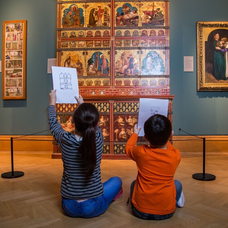 Two children seated on floor drawing museum exhibits