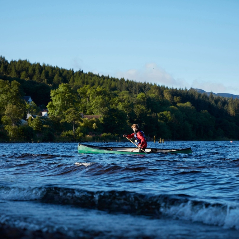 Man canoeing on Loch Ness on a clear sunny day.