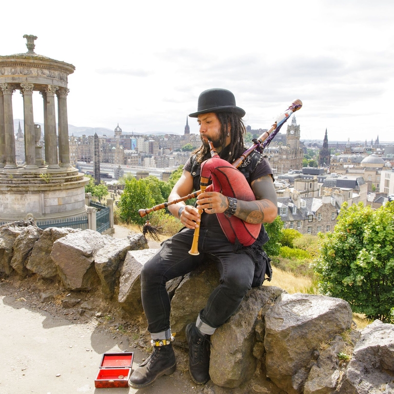Pedro De Lobo a travelling Spanish Bagpipe player sits above edinburgh on Carlton Hill