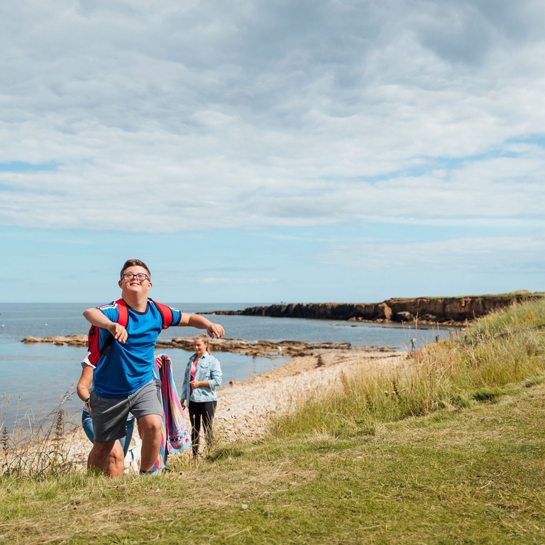 A young boy with Downs Syndrome playing on the beach