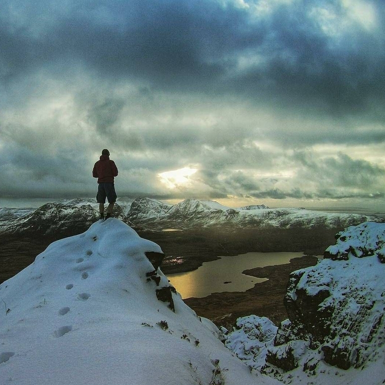 Person on snow-capped mountain top looking out across landscape