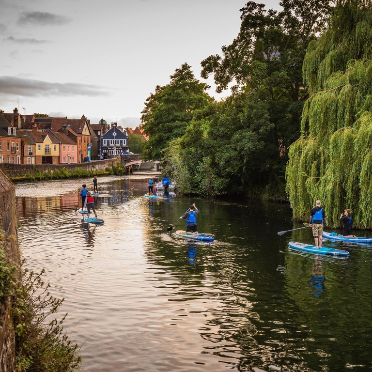 A group of people paddleboarding on the River Wensum