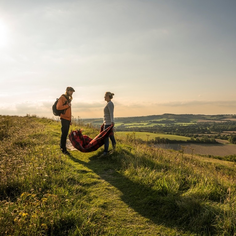 A couple walking on hilly landscape overlooking valleys