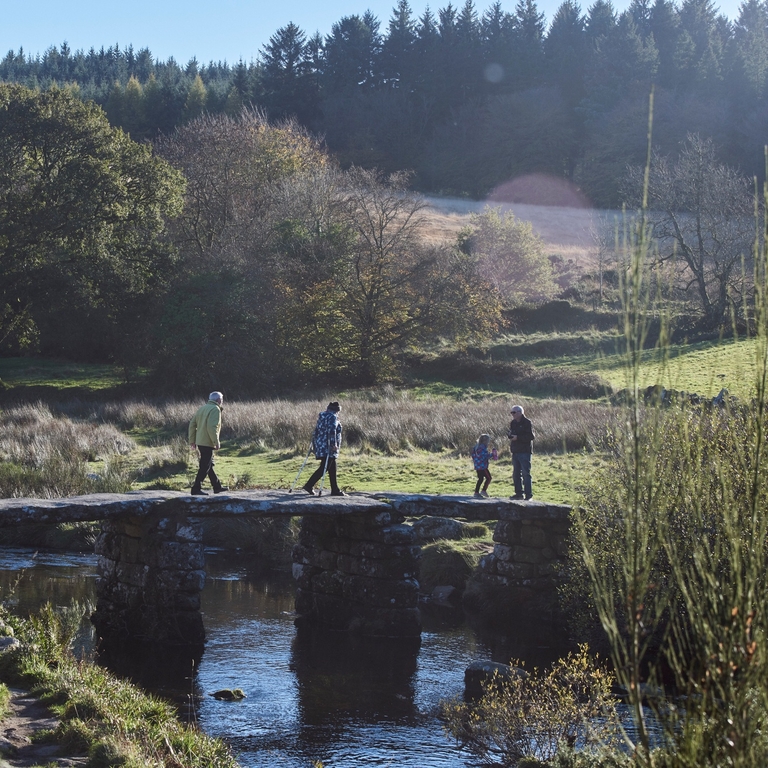 People walking on stone bridge across river