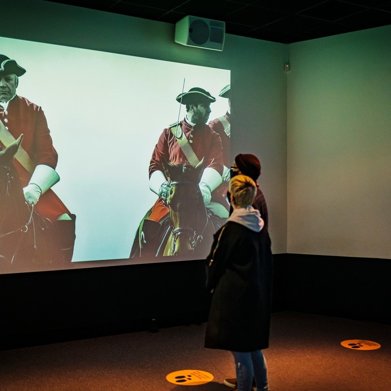 A pair of people watching a historical film at a museum in Scotland