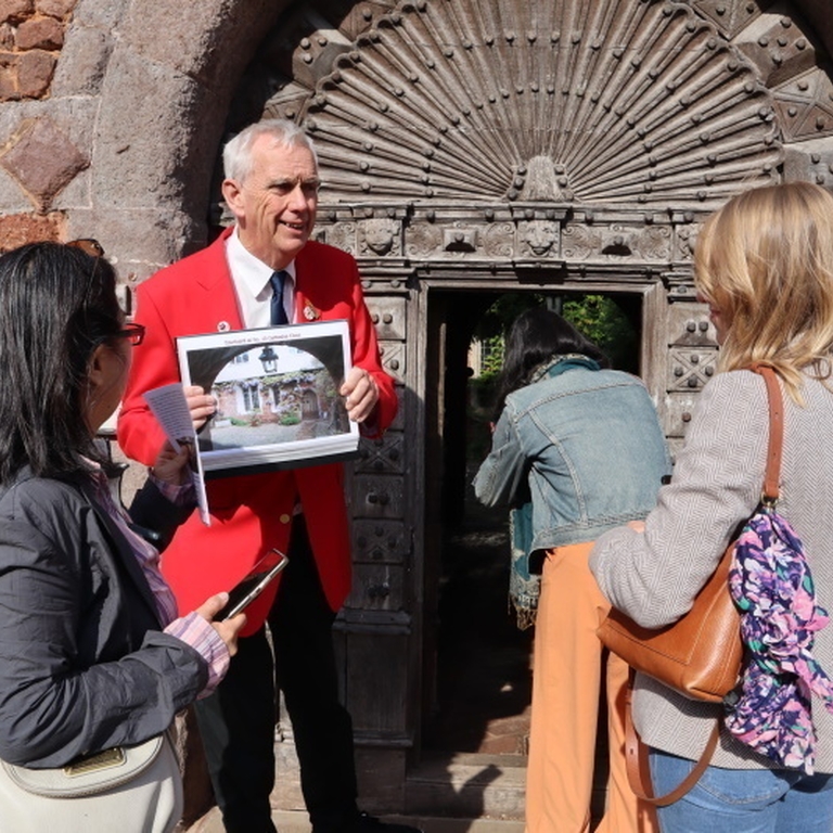 A tour guide in a red blazer leading a tour group around the centre of Exeter