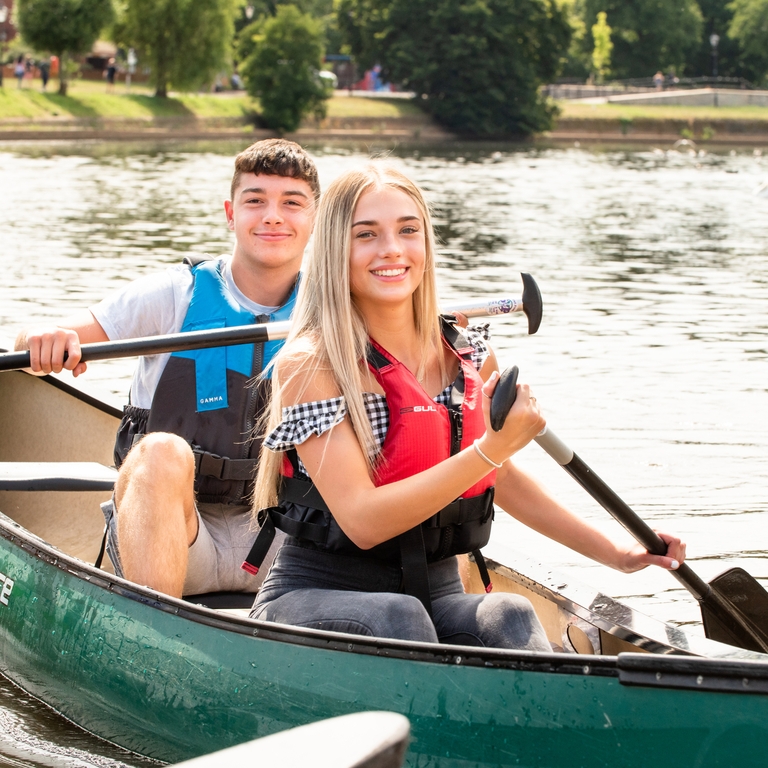 A man and a woman paddling a boat along the River Exe in Exeter