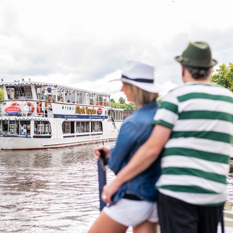 Two people looking at a boat arriving at a dock in Chester