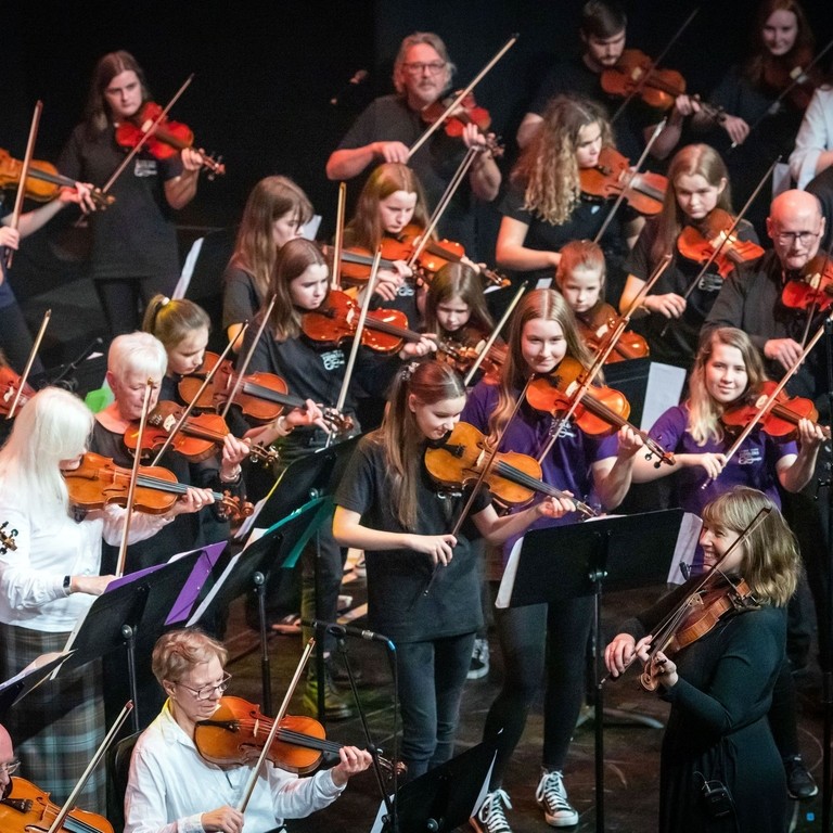 Patsy Reid performs on stage with fiddlers at the Our Language, Our Music concert at Perth Concert Hall during the Mòd 2022