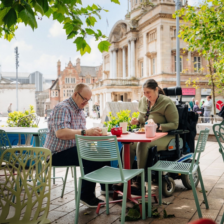 A man and woman sit at a table outside a cafe