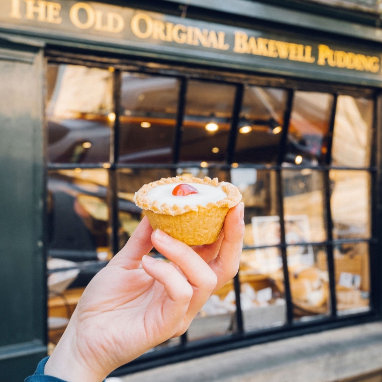 Hand holding Bakewell tart in front of bakery