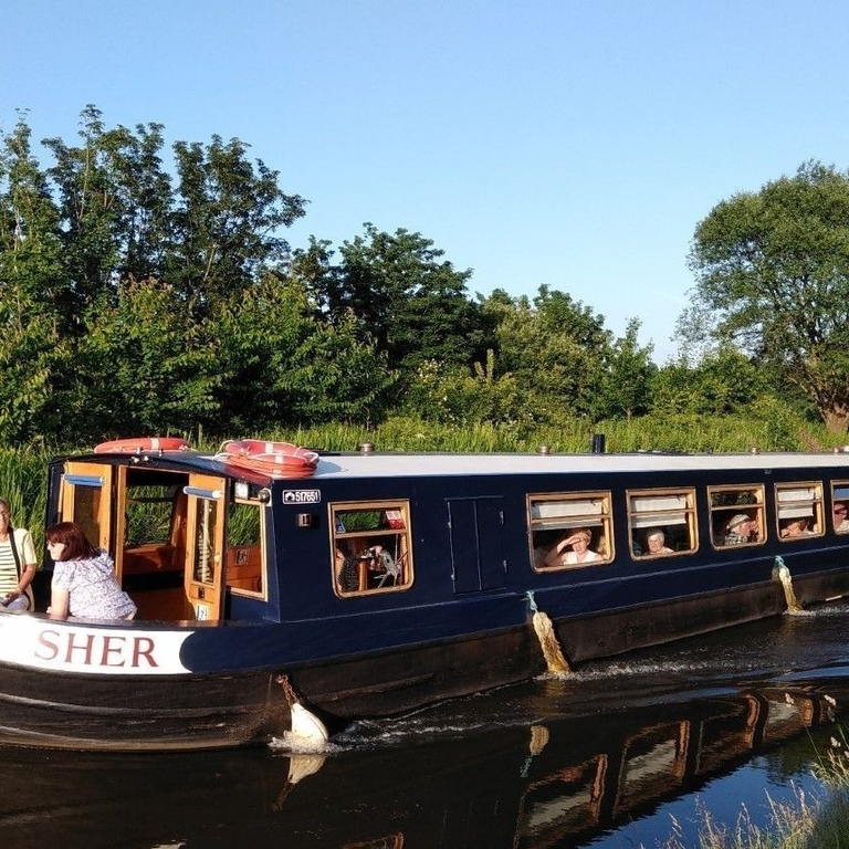 A group of people onboard a barge sailing down a river in Lancashire