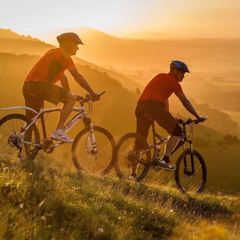 Two men on mountain bikes cycling at Devil's Dyke. Sunrise