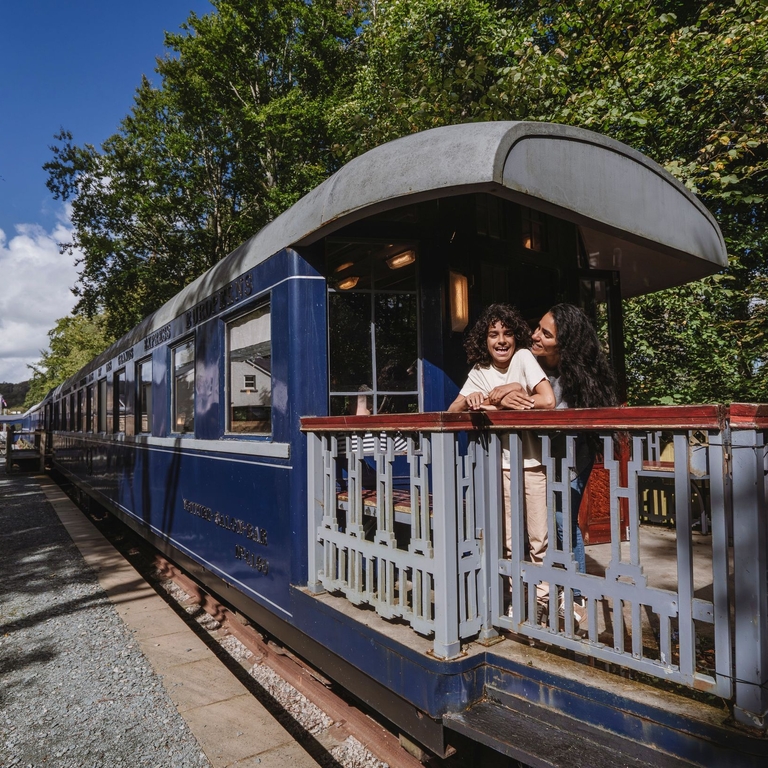 Mother and son smiling and hugging at the back of a heritage replica train.
