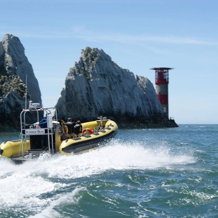 Boat passing chalk cliffs and a lighthouse