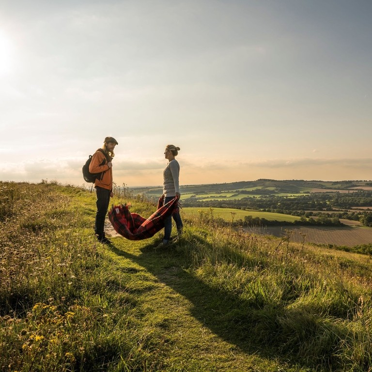 Una pareja paseando por un paisaje de colinas con vistas a los valles