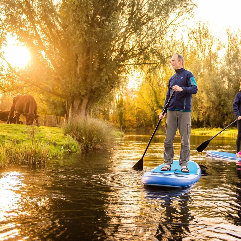 Two people paddleboarding down the River Bure