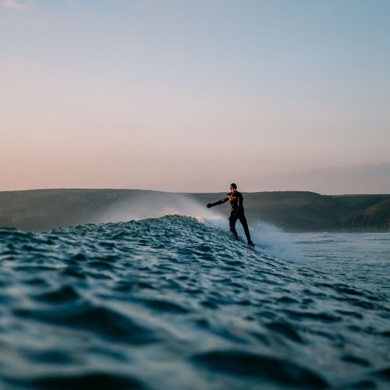 Man surfing in the evening with mountains in the distance