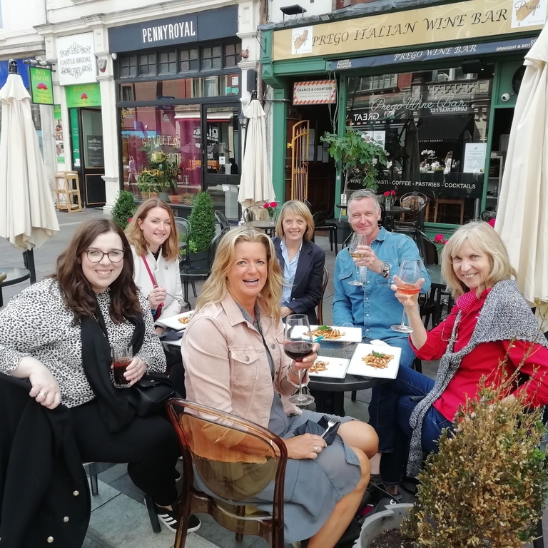 A group of people eating and drinking at an outside table at Cosmo, Cardiff
