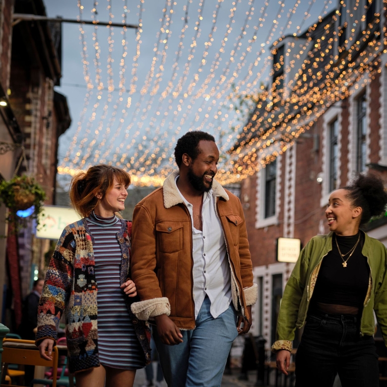 Friends exploring a cute shopping laneway lit up with fairy lights.