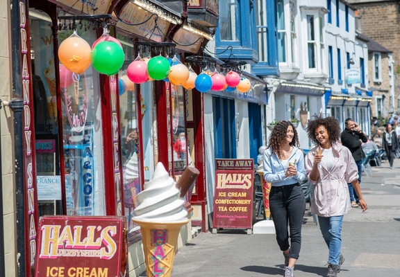 Two women walk down a street with ice creams