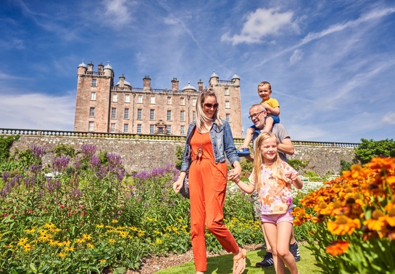 A young family walking through castle gardens.
