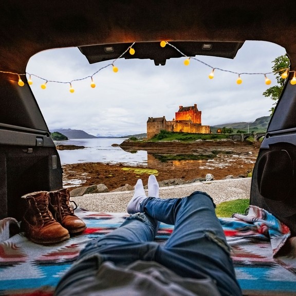 Uomo sdraiato in camper che guarda il castello in lontananza