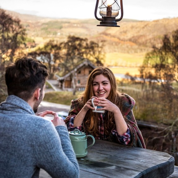 A couple seated, overlooking valley, having a hot drink