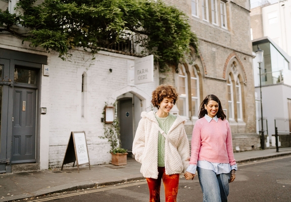 Two women leaving a cafe holding hands.