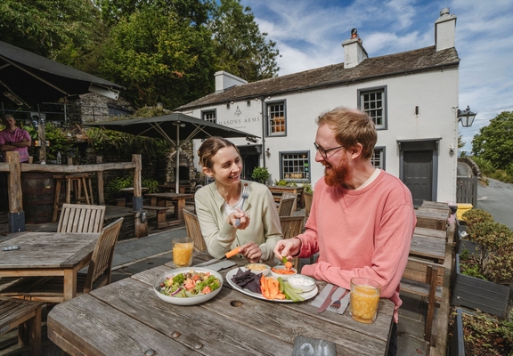 Man and woman having food whilst sitting at an outdoor table at a country pub.