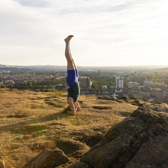 Young woman doing yoga on a hill overlooking a city
