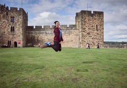 Young woman hovering on a broomstick in the Outer Bailey of Alnwick Castle