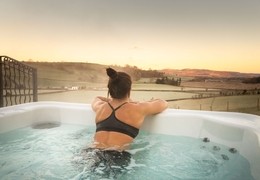 A woman in a hot tub outdoors overlooking the countryside.
