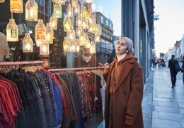 Woman looking through shop window at clothes and lamps