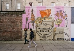 A man and a woman walking past the marmalade mural.