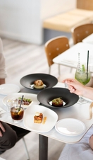 A man and a woman sit at a table with food and drinks inside a restaurant 