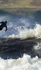 A surfer riding waves off the coast of the UK