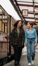 Three people walking along a train platform. 