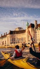 Two people kayaking on the Thames towards the London Eye