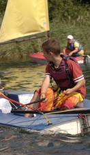 A child sailing a boat on a river in the Broads National Park