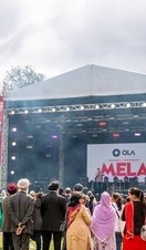 Crowd of people in front of a stage at the Mela Festival watching a performance