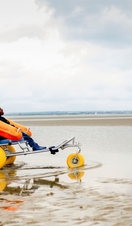 A woman with her son who sits in an accessible sea wheelchair with floats on a beach