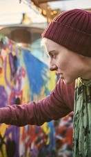One young woman using aerosol to create street art mural