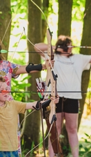 A family learn archery skills in a woodland setting