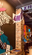 Large wall mural of a funky zebra hodling a cocktail saying "Amazing" inside the bar at CC Blooms.