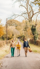 Two women and a man walking on a country lane in autumn
